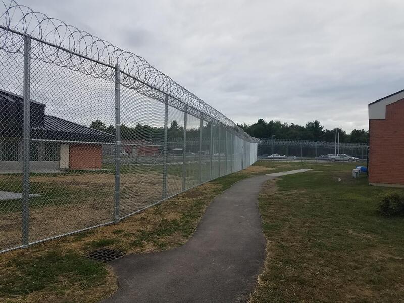 Chain link security fence topped with razor wire coils