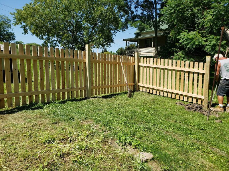 Natural dog ear picket fence being installed by builder