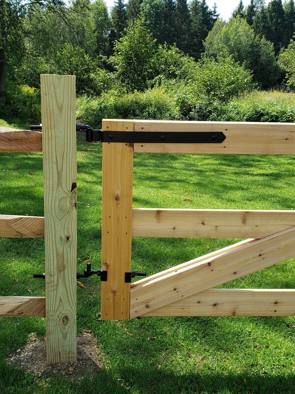 Natural wood split rail and post fencing and gate entrance with black steel fastenings