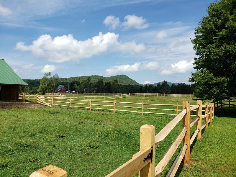 Natural wood split rail and post fencing surrounding farm fields