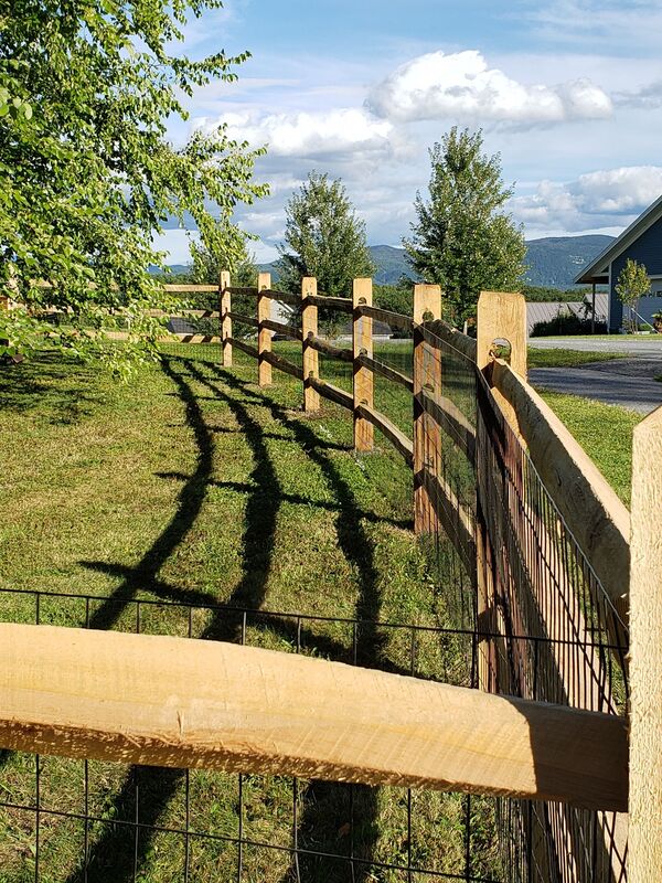 Natural wood split rail and post fencing surrounding farm fields