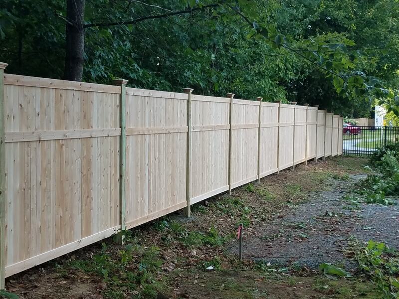 Solid board dog ear fence with post caps along edge of property