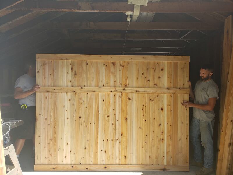 Guys carrying solid board dog ear fence building inside shed